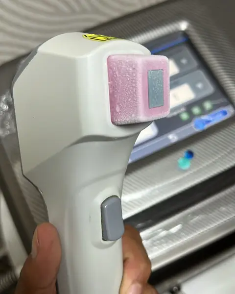 Mão segurando a ponteira do Galaxy Fiber Evo, com a janela de luz rosa, diante da tela do aparelho